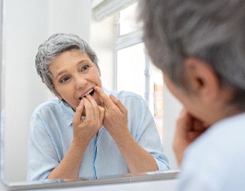 woman flossing her dental implants in Canton