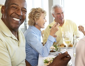 Smiling man with dental implants in Canton eating healthy with friends
