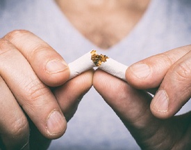 Closeup of patient with dental implants in Canton breaking cigarette