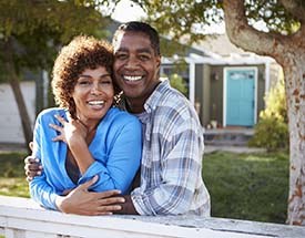 happy couple with dental implants in Canton standing in their front yard 