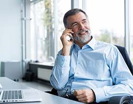 businessman sitting at a desk while talking on the phone 