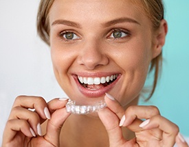 Smiling woman holding Invisalign tray