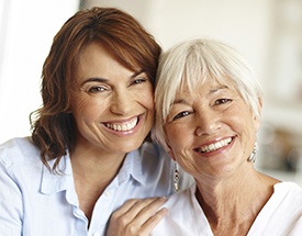 Smiling adult daughter and older mother