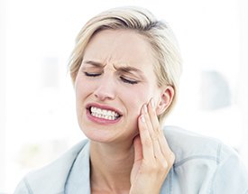 Woman grimacing and holding cheek