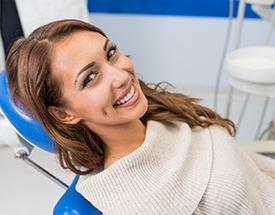 a smiling woman laying back in a dental chair