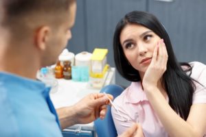 A woman with tooth pain listening to a dentist.