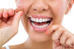 woman smiling flossing her teeth