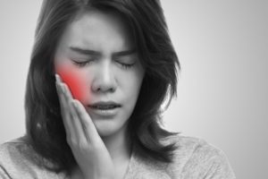 pained woman with toothache puts her hand to her cheek 