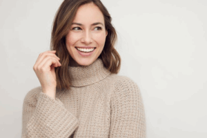 Woman in cozy sweater smiling on a white background