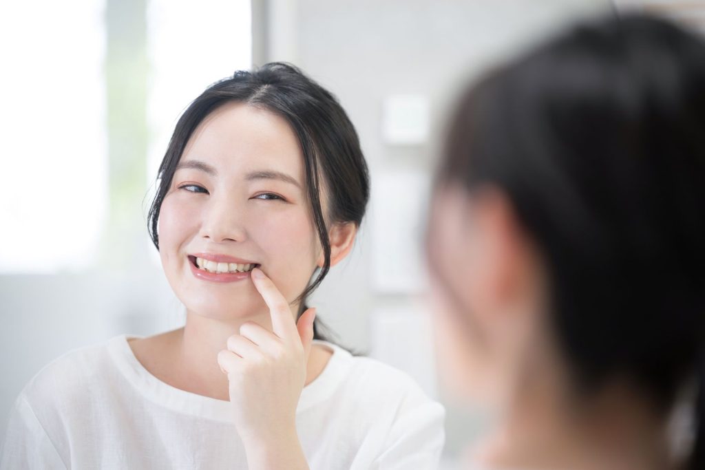 A woman looking in the mirror at her smile